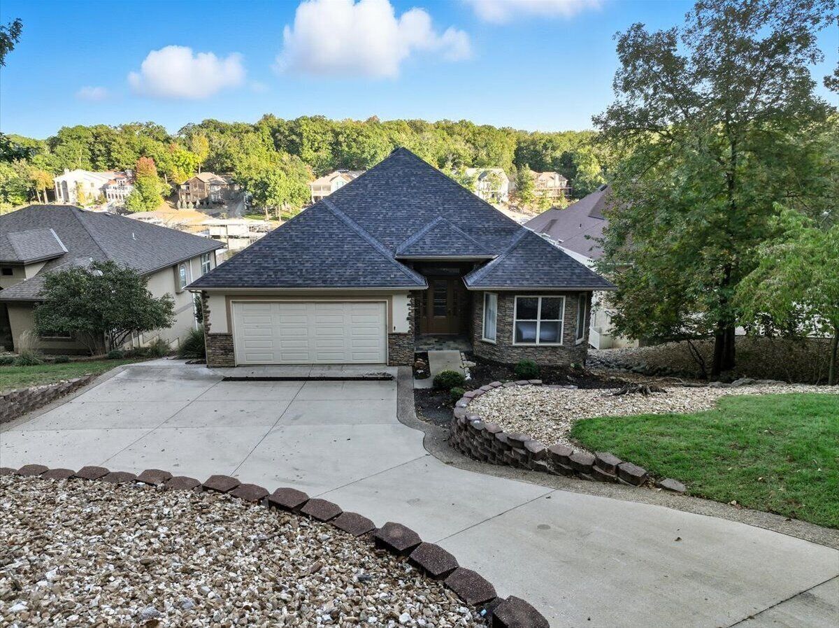 A single-story house with a garage, surrounded by a landscaped driveway and a gravel border.