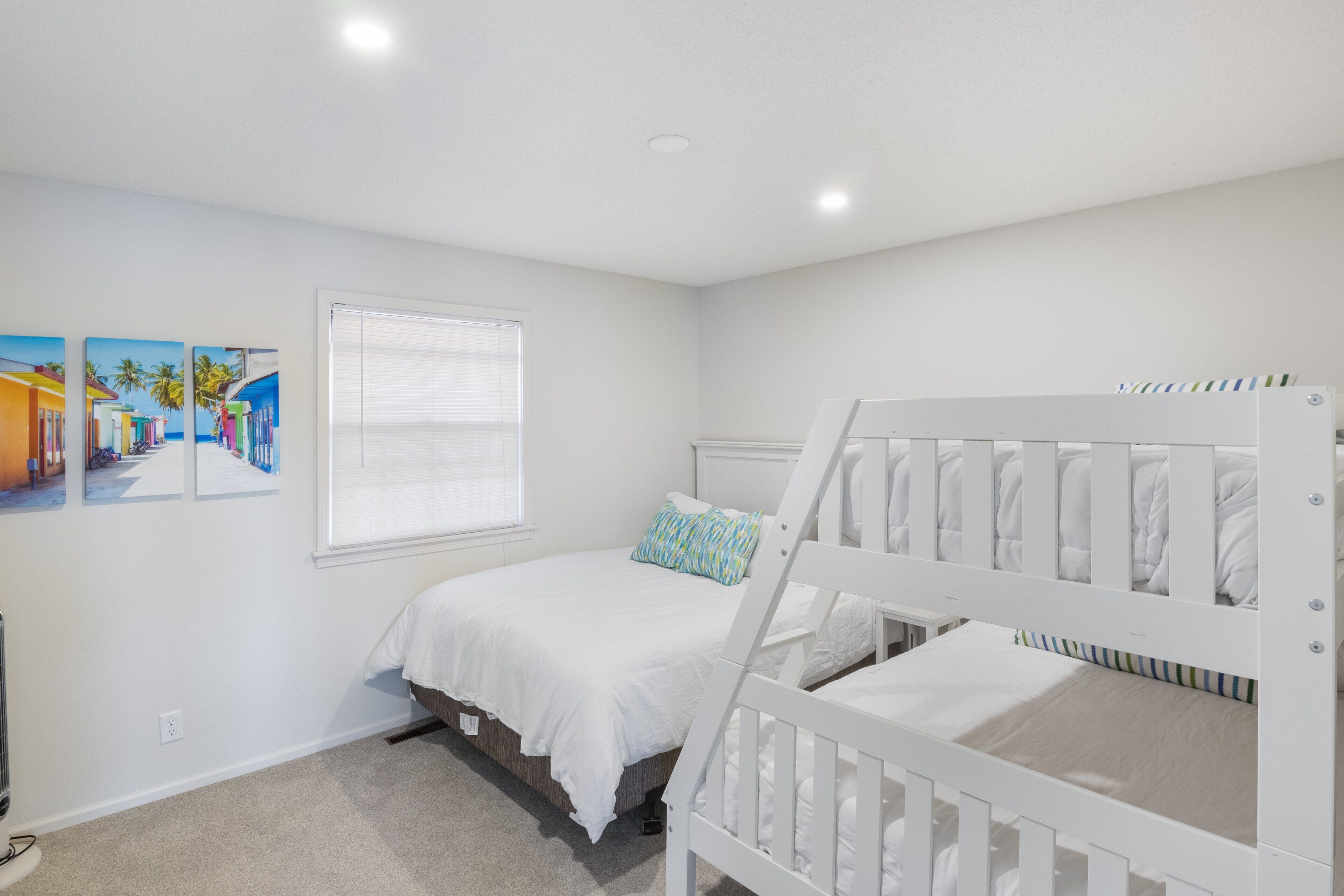 Un dormitorio con una cama litera, una cama individual, una ventana con persianas y un estante en la pared.