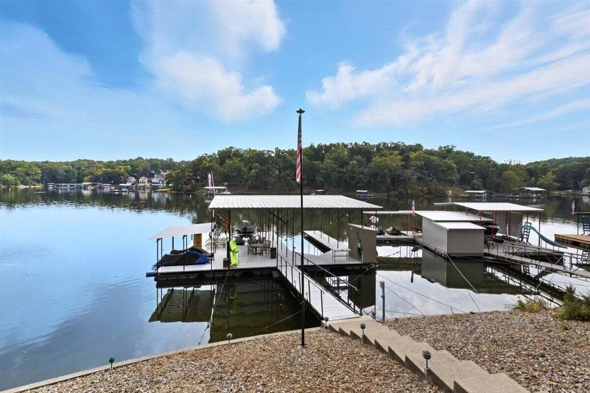 Un muelle con un asta de bandera, barcos y un edificio con un porche.