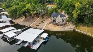 A lakeside property with a house, dock, and covered boat storage. - Expansive Deck, Beautiful Views, Private Dock & Boat Slip (Sunrise Beach)