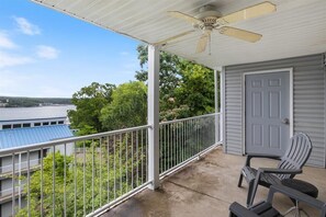En balkon med ventilator, udsigt til vand og en dør til højre.