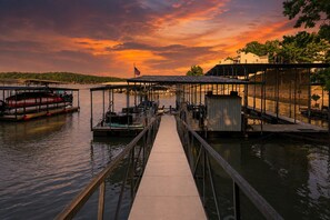 Un quai au bord de l’eau, avec un bateau, une passerelle couverte et un petit bâtiment.