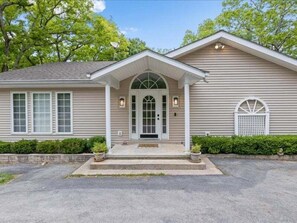 A two-story house with a front porch, a garage door, and a small front yard.