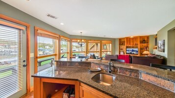 Una cocina moderna con encimeras de granito, un lavamanos de acero inoxidable y armarios de madera.