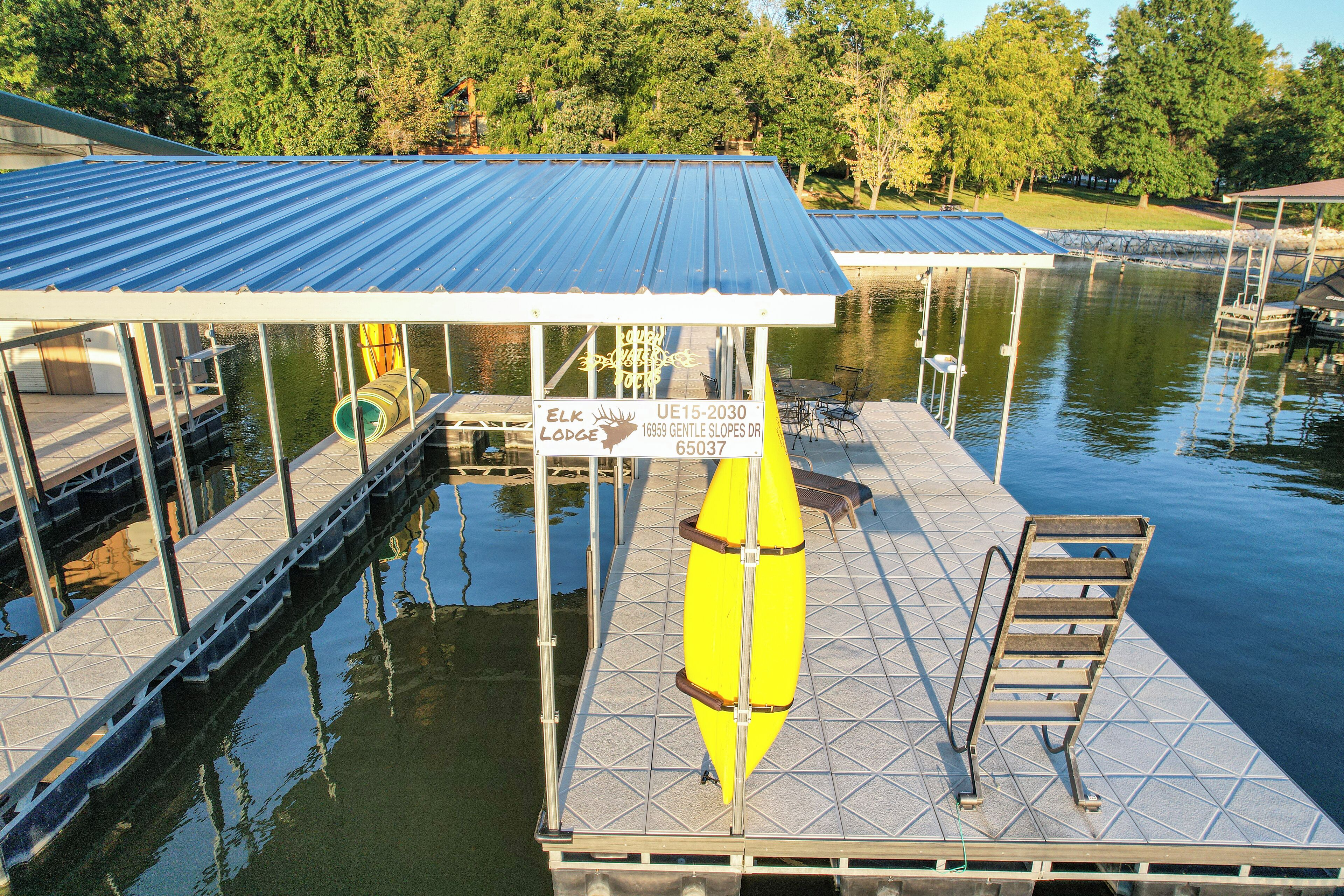 A dock with a covered seating area, a kayak, and a sign for Elk Lodge.