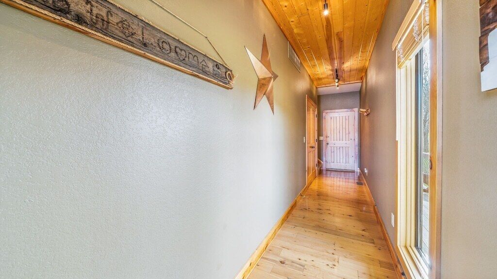 Um corredor com piso de madeira, um adorno em formato de estrela e uma porta no final.