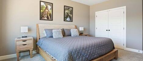 A bedroom with a bed, two nightstands, a ceiling fan, and a door.