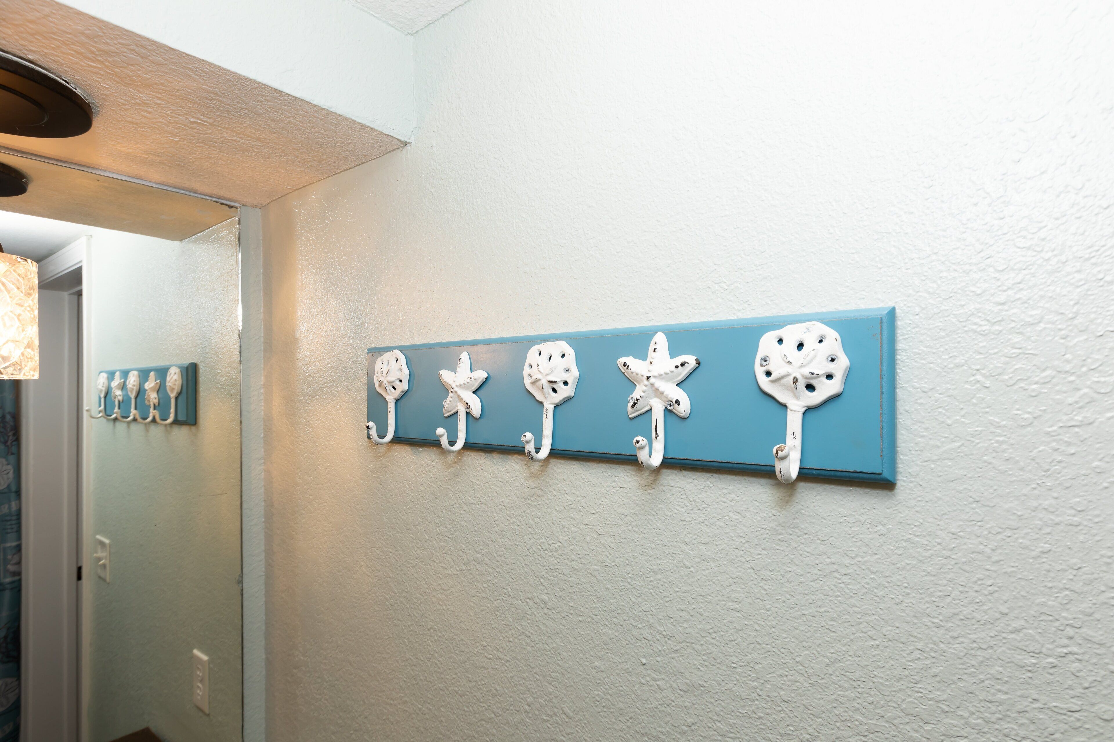 A hallway with a blue wall and a series of white wall hooks.