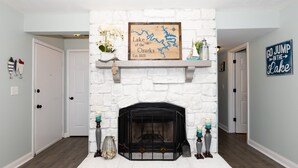 A fireplace with a stone facade, a framed map above it, and a sign on the wall to the right.