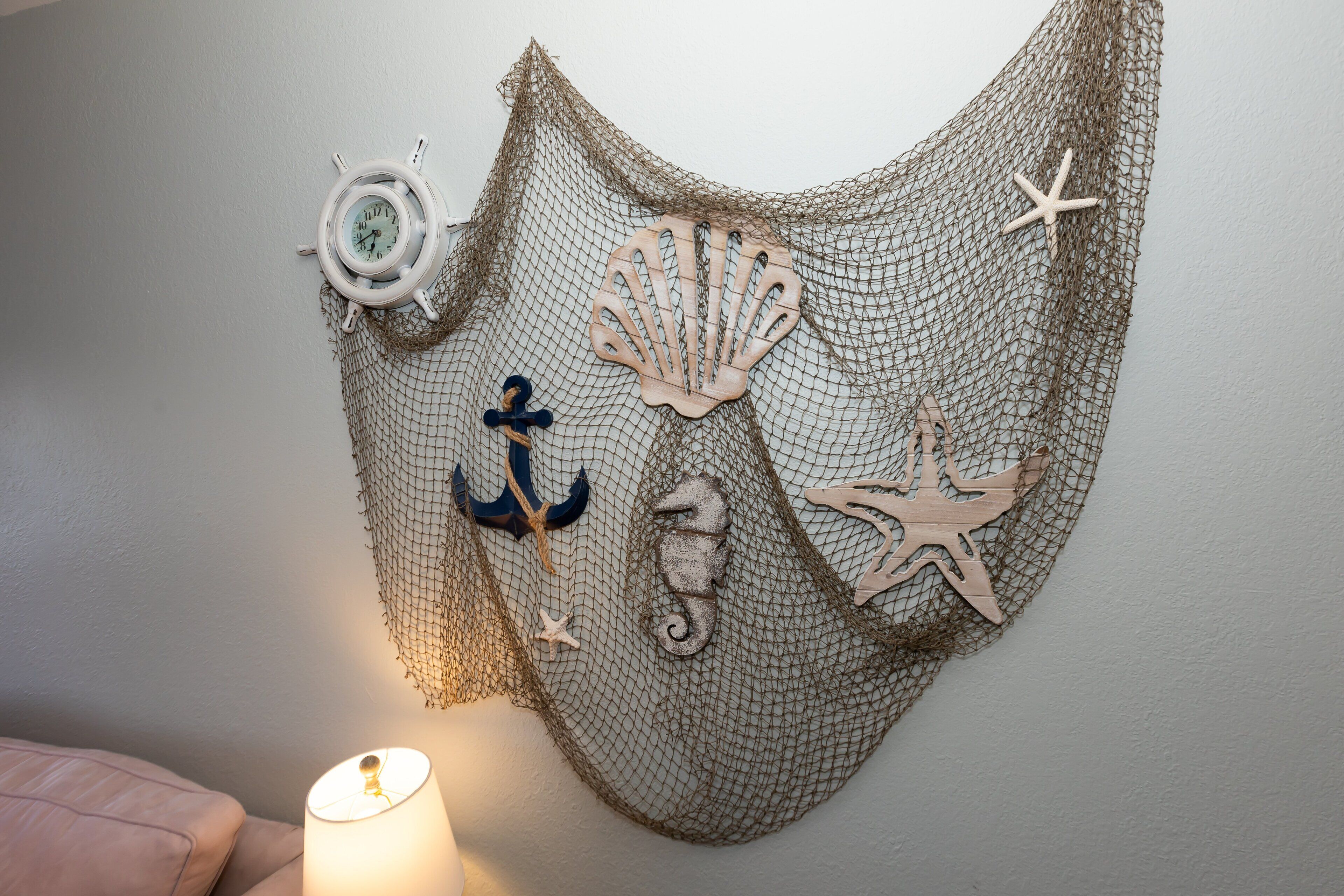 Un élément décoratif à accrocher au mur, agrémenté de motifs marins tels qu’un gouvernail de navire, une ancre et des étoiles de mer.