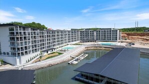A modern hotel with a large glass facade, a swimming pool, and a dock area.