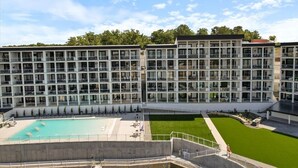 A multi-story hotel with a swimming pool, outdoor seating, and a well-maintained lawn. - Family-fun Lakeside Luxury at Topsider in Osage w/ 2 Pools, Prime Views Pack N' Play & Games (Osage Beach)