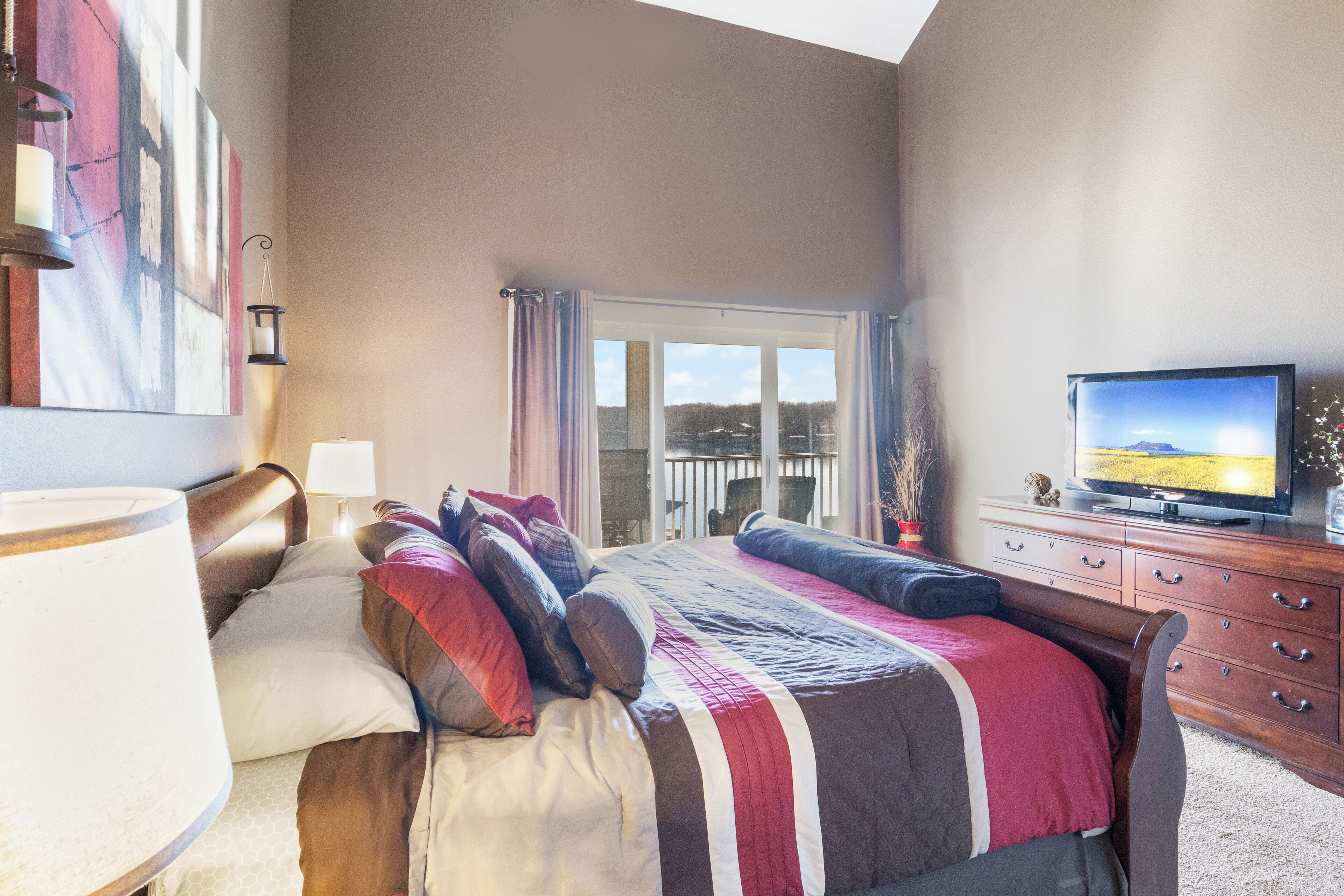Un dormitorio con una cama grande, televisión y balcón con vistas.