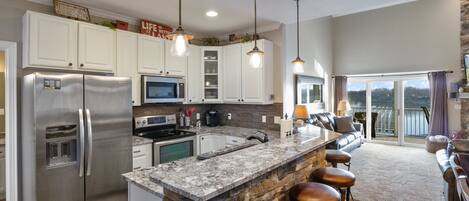 Una cocina moderna con una isla grande, electrodomésticos de acero inoxidable y una pared decorativa de piedra.