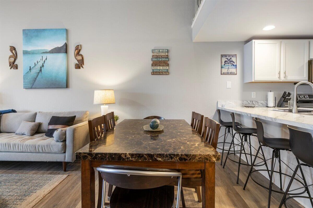 Een moderne keuken met witte kastjes, een marmeren aanrecht en barstoelen.