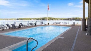 A swimming pool with lounge chairs and an American flag, surrounded by a white fence and a view of a lake. - Family-perfect Lakefront Fun at The Ledges, 21mm, 2 Pools & Beach (Osage Beach)