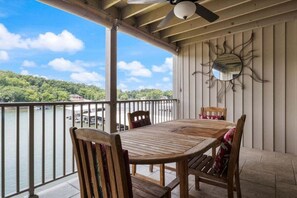 A wooden table and chairs on a balcony with a view of a lake and trees. - Stunning Views, Inviting Pools, and Endless Fun! (Osage Beach)