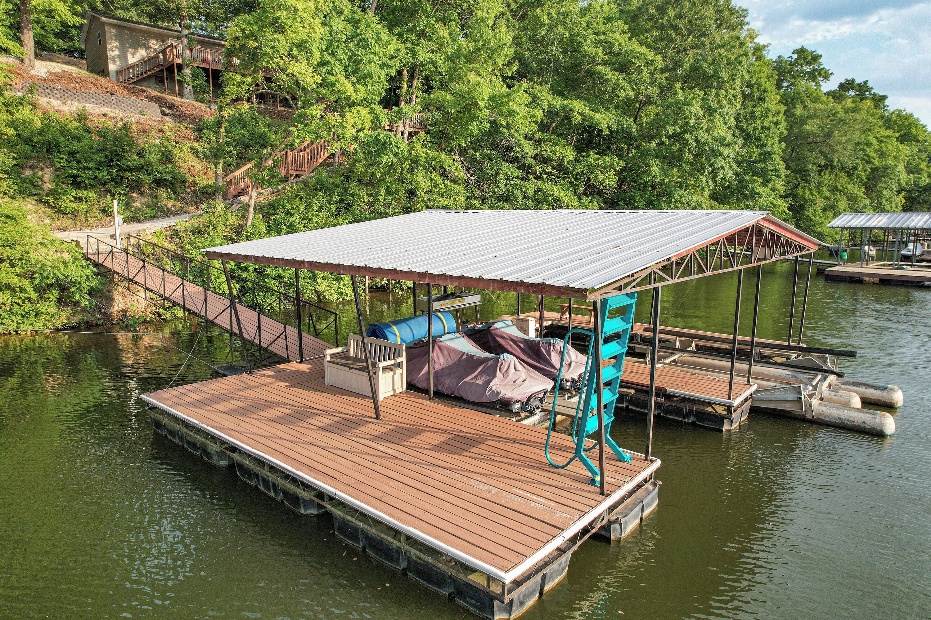 A wooden dock with a covered seating area and a small boat.