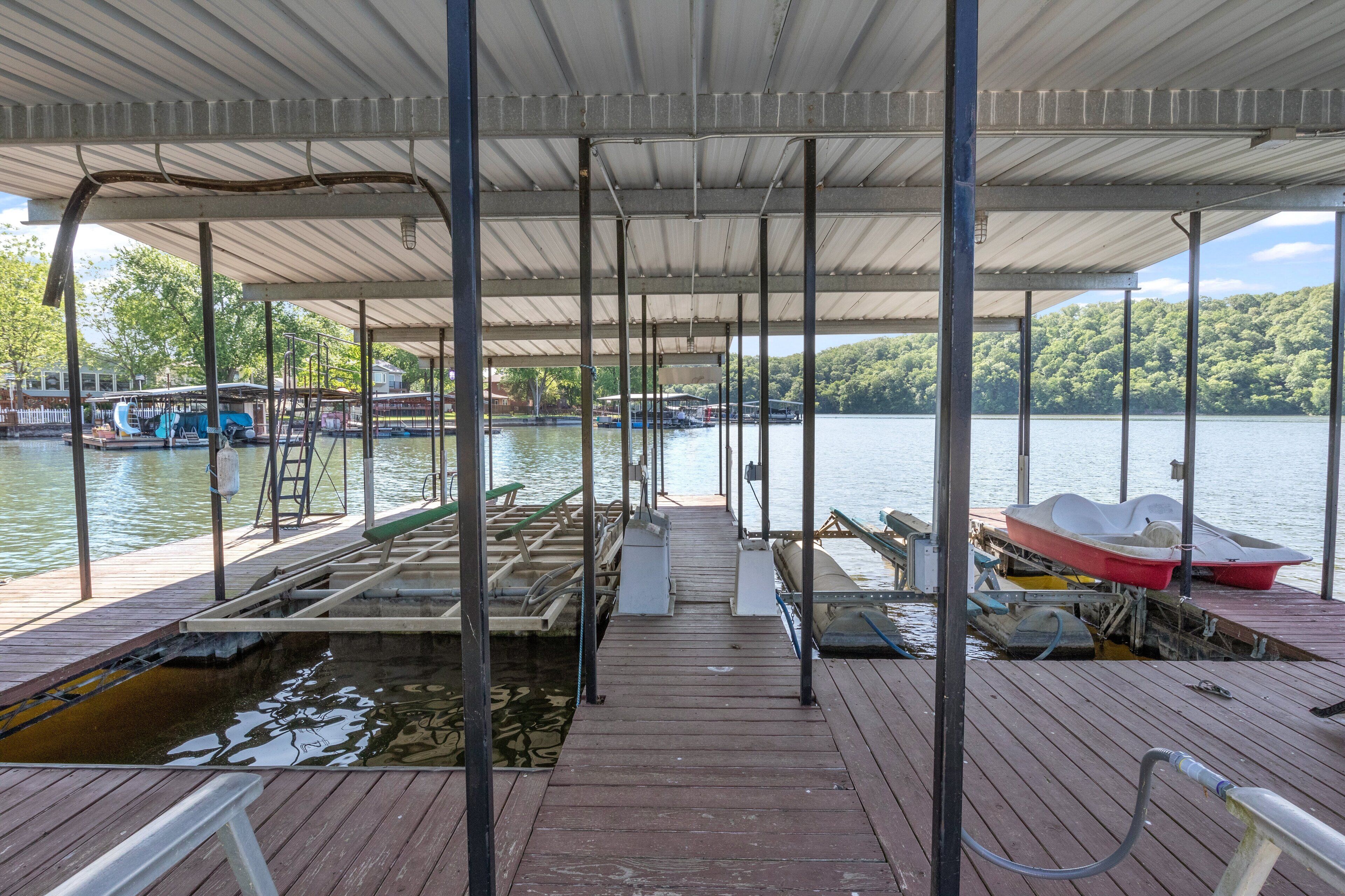 A covered dock with boats and a wooden walkway leading to the water.