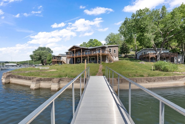 A waterfront property with a dock leading to a house with a balcony.