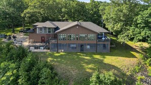 A two-story building with a large glass facade, a covered outdoor seating area, and a well-maintained lawn. - 17 Lakefront Acres, Private Dock, Firepit, Pool Table, Kayaks, Fishing (Gravois Mills)