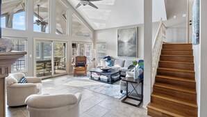 A spacious living room with a high ceiling, large windows, and a wooden staircase. - Family-friendly, Dock Enjoyment, Kayaks, Lake View (Sunrise Beach)