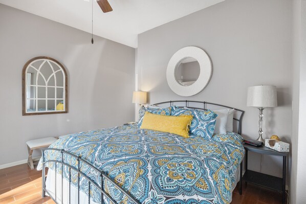 A bedroom with a bed, bedside table, lamp, and a window with a decorative frame.