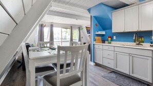 A kitchen with white cabinets, a blue accent wall, and a dining area with a white table and chairs. - Pet Friendly A Frame w/ Private Dock & Great Lake Views (Rocky Mount)
