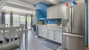 A modern kitchen with white cabinets, a stainless steel refrigerator, and a blue accent wall. - Pet Friendly A Frame w/ Private Dock & Great Lake Views (Rocky Mount)