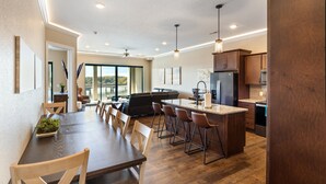 Une cuisine moderne dotée d’un îlot central, d’un plancher en bois et d’un coin repas avec une longue table et des chaises.