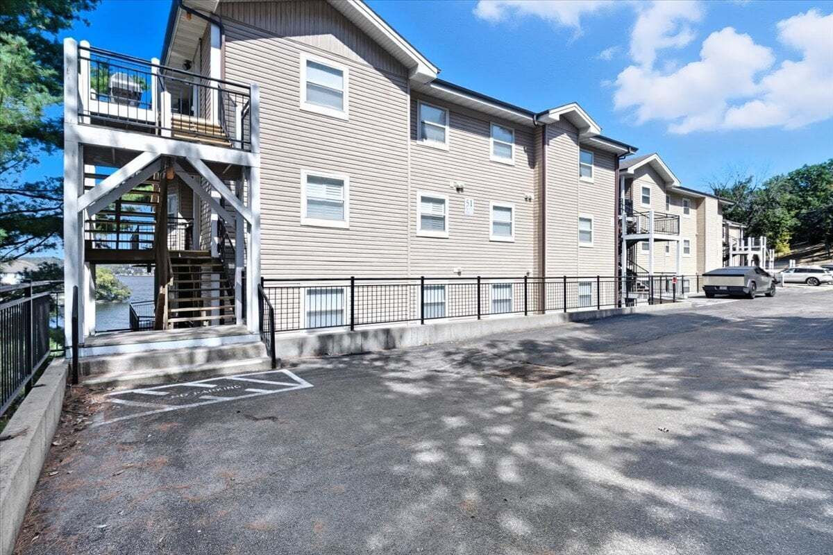 Un immeuble à plusieurs étages doté d’un parking au niveau du sol et d’un escalier menant à un étage supérieur.