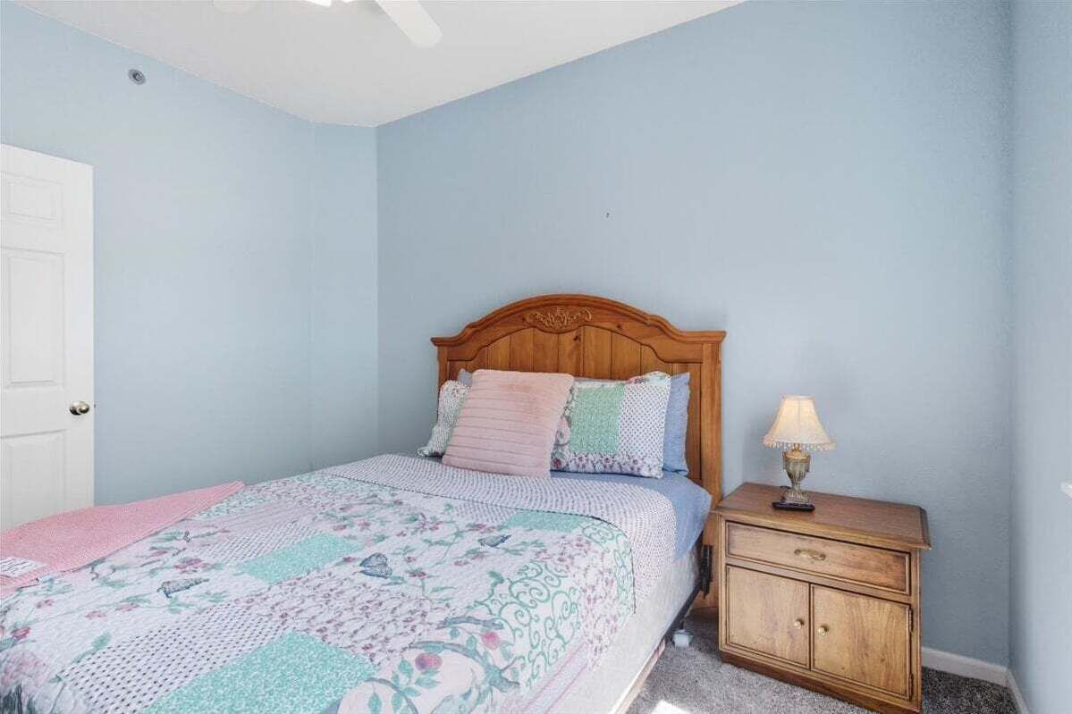 A bedroom with a wooden bed, a nightstand, and a lamp.