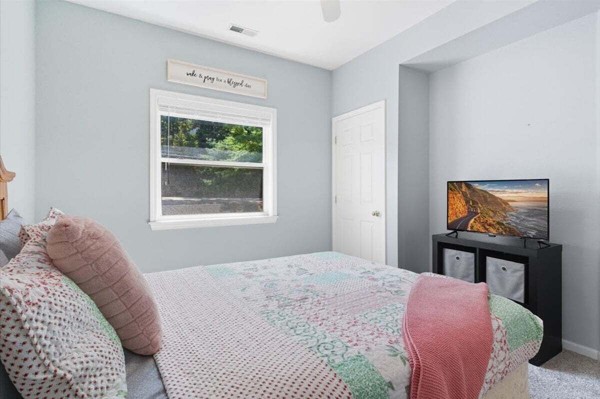 Ein Schlafzimmer mit einem Bett, einem Fenster, einem Fernseher und einer Tür.