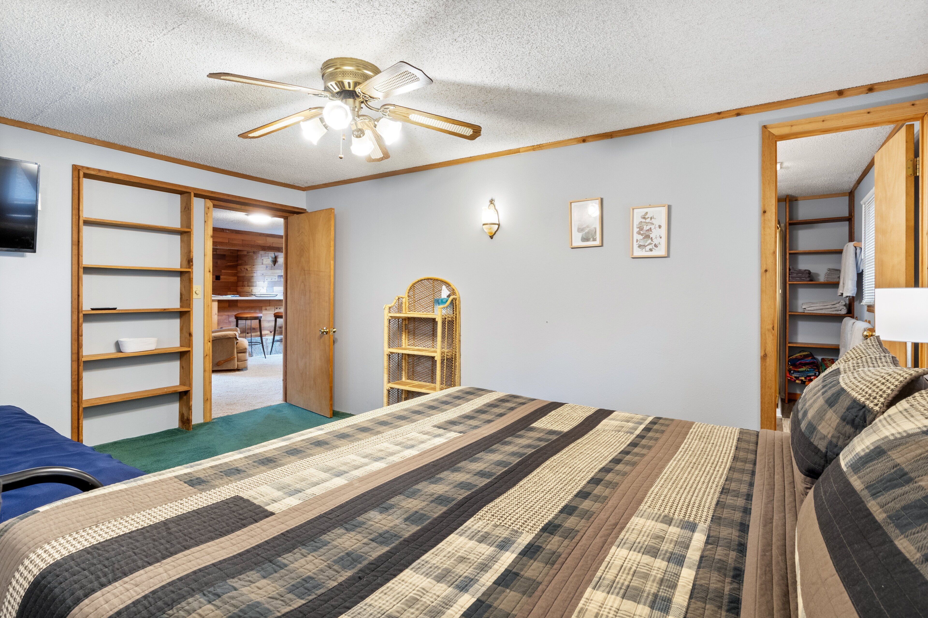 Ein Schlafzimmer mit Bett, Deckenventilator, Kleiderschrank und einem durchgehenden Türbogen erreichbarem Badezimmer.