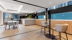 A modern kitchen with a central island, a dining area with a table and chairs, and a view of a pool through large windows. - 2-bed Inner-city Pad With Pool, (Melbourne)
