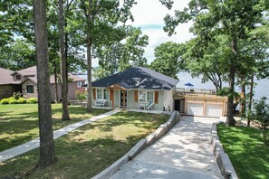 Une propriété résidentielle dotée d’un patio couvert, d’un garage et offrant une vue sur un lac.