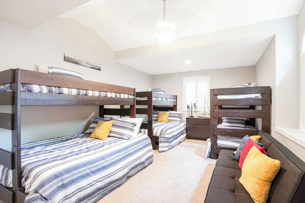 A room with bunk beds, a sofa, and a bedside table. - Two Homes, Large Deck, Firepit, Central Location (Sunrise Beach)