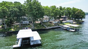 Een pand aan de rivier met een steiger, een klein bootje en een huis met balkon met uitzicht op het water.