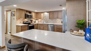 A modern kitchen with a large island, built-in appliances, and a stone backsplash. - Quiet Cove, Private Dock, Fishing, Swimming, Boat Slip & Kayaks (Camdenton)