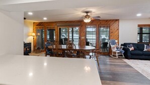 A spacious living room with a large dining table, wooden accents, and a fireplace. - Quiet Cove, Private Dock, Fishing, Swimming, Boat Slip & Kayaks (Camdenton)