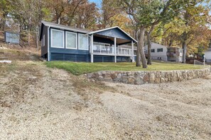 A two-story house with a covered porch, a stone retaining wall, and a grassy yard. - Sunset & Lake Views, Outdoor Dining & Seats (Gravois Mills)