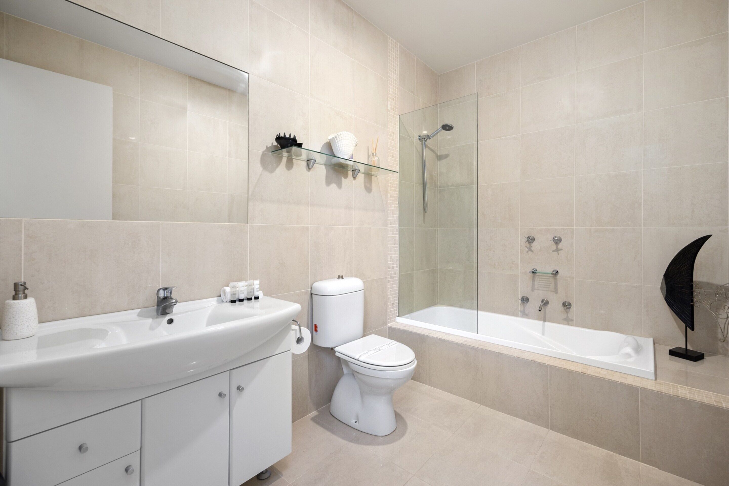 A modern bathroom with a large sink, toilet, and bathtub.