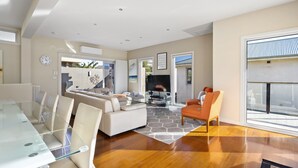 A modern living room with a glass dining table, a sofa, and a coffee table. - Spacious 3-bed Townhouse Near Dromana Beach (Melbourne)
