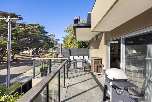 Un patio extérieur moderne avec une balustrade en verre, un scooter et un barbecue.