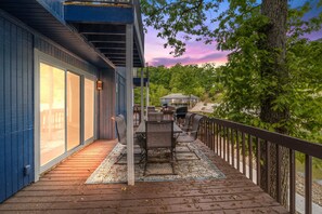 Una terraza con mobiliario exterior, barandilla y vista a una casa y árboles.