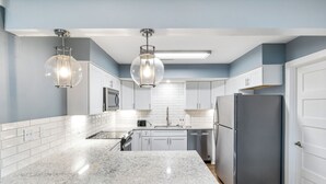 A modern kitchen with white cabinets, a granite countertop, and stainless steel appliances. - Our Cove Retreat - Perfect for Wave-free Swimming, Tanning & Prime Location Fun! (Lake Ozark)