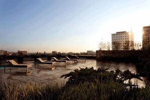 A rooftop pool area with lounge chairs and a view of a cityscape.