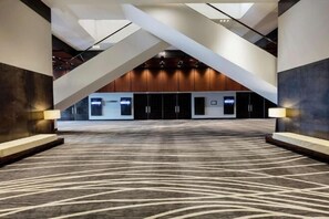 A spacious indoor area with a patterned carpet, a staircase, and a reception desk.