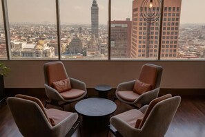 A room with four armchairs and a small table, large windows with a cityscape view, and a chandelier. - Hilton Mexico City Reforma (Mexico City)