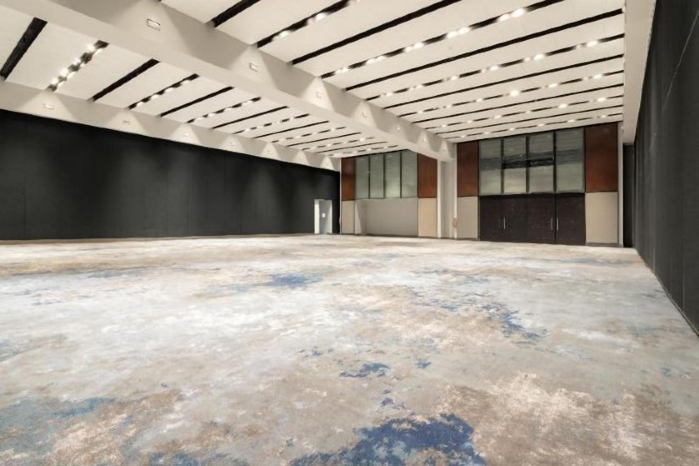 Um espaço interno amplo, com teto alto, piso livre e parede escura.